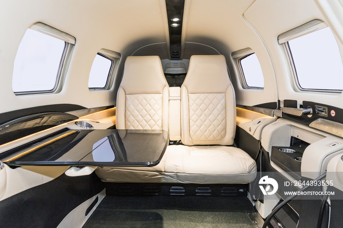 View into the cockpit of a sports plane. A look into the cockpit of a modern sports aircraft. Bright leather seats and a serving table in the cabin.