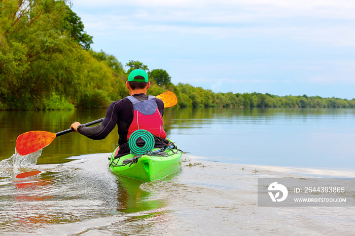 Man paddling in green kayak on a Danube river. Water tourism. Kayaking.