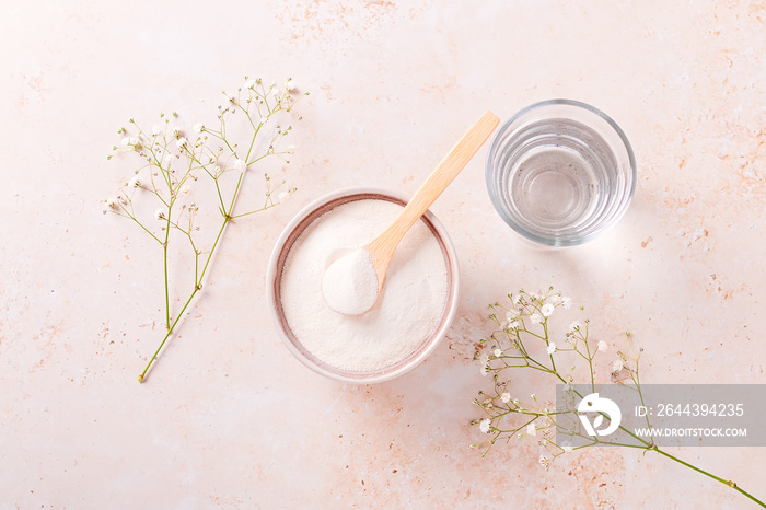 Collagen powder and glass of water on beige stone background, top view