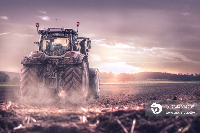 Traktor erntet bei Sonnenuntergang