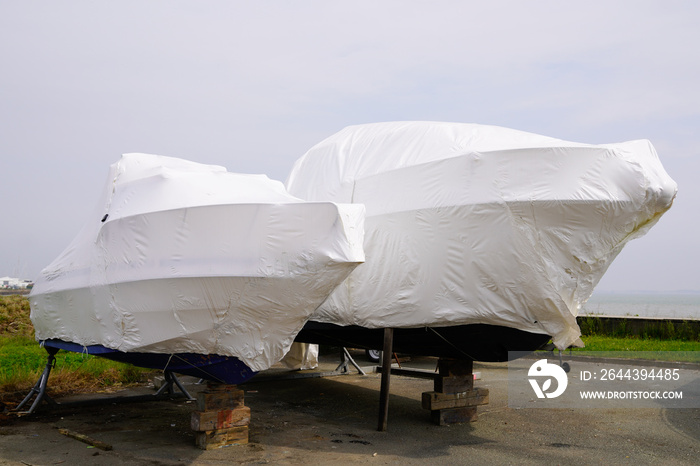 power boat parked water protected by plastic film for wintering New boats in cover casing shrink wrap on sailboat stored for winter