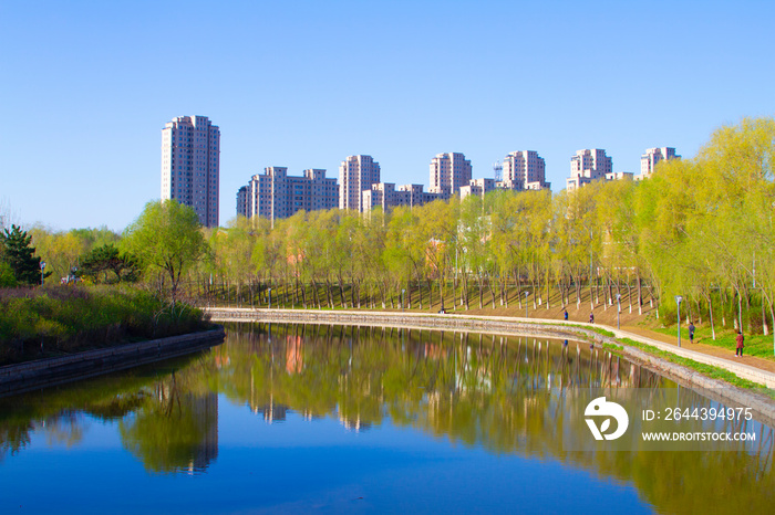 Modern apartment buildings by a lake with shadows in the water mirror reflection Spring