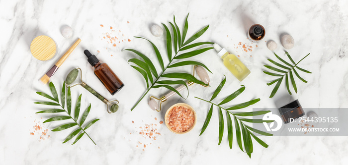 Natural SPA cosmetic products background, Composition with bottles of essential oils, sea salt and massage rollers on white marble background