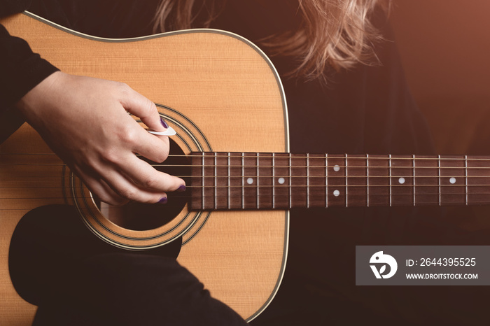 girl plays an acoustic guitar. close-up of strings