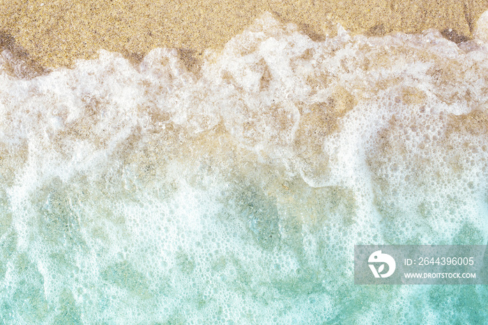 Soft waves with foam on sandy beach. Top view.