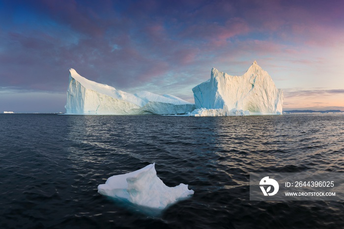 Iceberg at sunset. Nature and landscapes of Greenland. Disko bay. West Greenland. Summer Midnight Sun and icebergs. Big blue ice in icefjord. Affected by climate change and global warming.