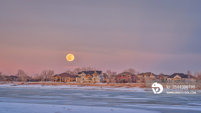 full moon rising over houses at waterfront of Boyd Lake in northern Colorado, winter scenery