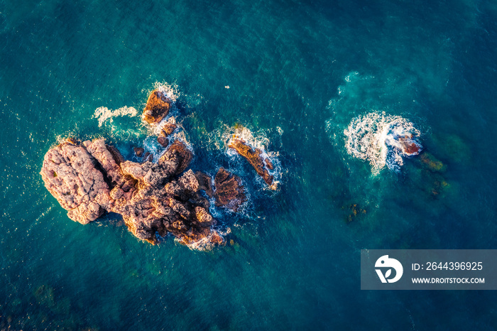 Top down view of volcanic rocks in Mediterranean sea. View from flying drone of the shore of Milazzo peninsula. Stunning spring scene of Sicily, Italy, Europe. Beauty of nature concept background.