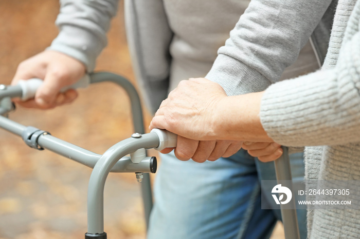 Elderly woman and her husband with walking frame outdoors, closeup