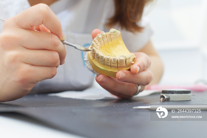 dental technician shaping a prosthesis tooth
