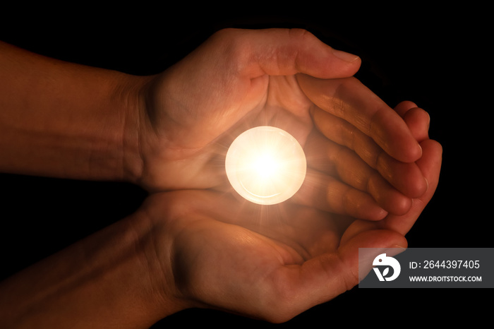 Hands holding and protecting lit or burning candle candlelight on darkness. Black background. Concept for prayer, praying, hope, vigil, night watch