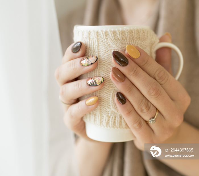 hands of autumn nails holding a cup of hot tea