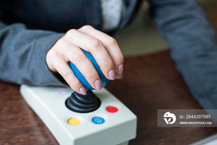 Woman with cerebral palsy works on a specialized computer mouse.