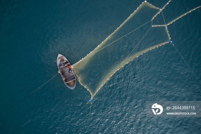 Vintage wooden boat in coral sea. Boat drone photo. A fisherman on a fishing boat is casting a net for catching fish