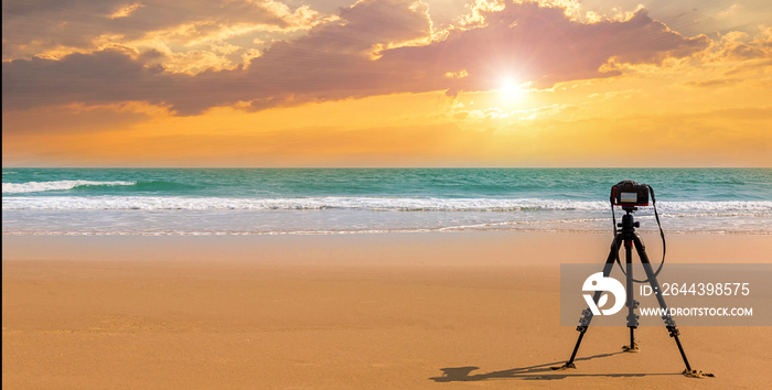 Digital professional camera stand on tripod photographing sea. Twilight sky background. Colorful Sunset sky and cloud.vivid sky in twilight time background.Fiery orange sunset sky. Beautiful