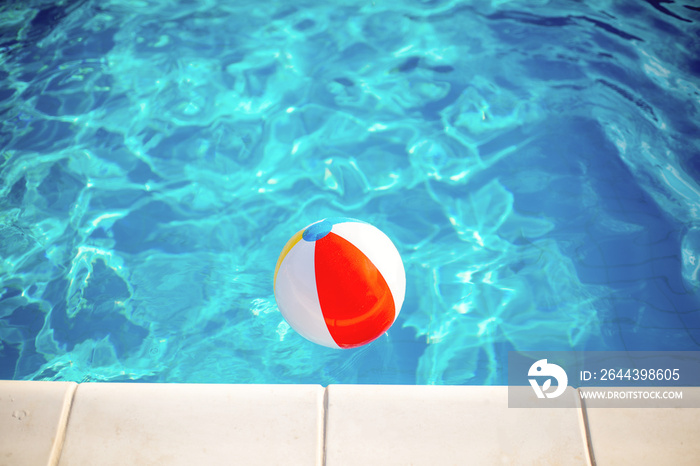 View from above on the inflatable colorful ball floating at the swimming pool with blue water