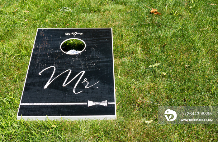 Black cornhole board with Mr written on it