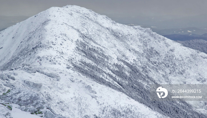 Three hikers seen in the distance trekking their way from Mount Lincoln to Mount Lafayette -White Mountains, New Hampshire