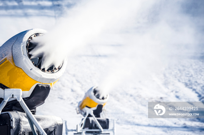 Snow cannon in winter mountains. Snow-gun spraying artificial ice crystals. Machine making snow.