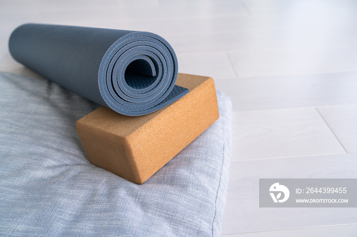 Yoga mat, cork block meditation pillow eco-friendly sustainable fitness products shopping. Natural organic material props for wellness studio on wooden floor background.