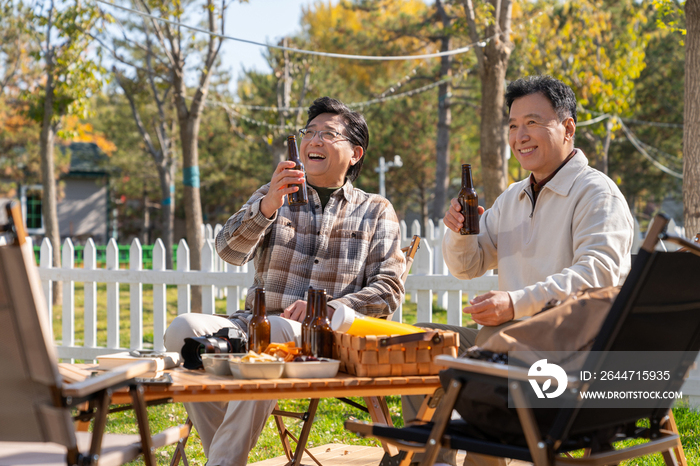 两个老年男人坐在露营地喝啤酒