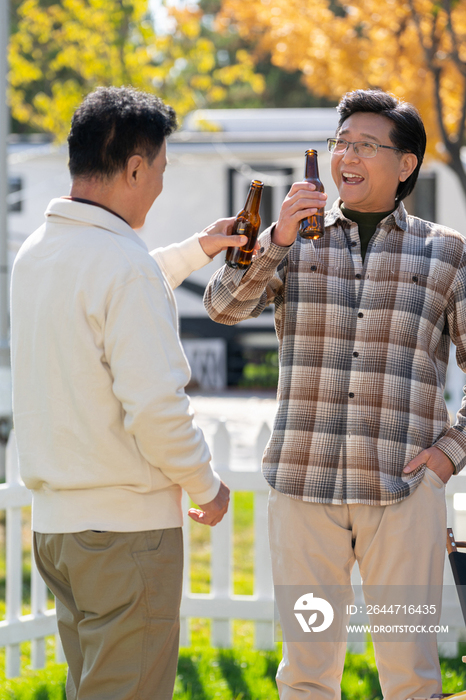 两个老年男人站在露营地喝啤酒
