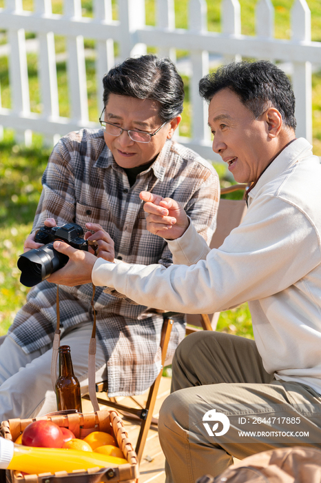 两个老年男人坐在露营地看数码相机