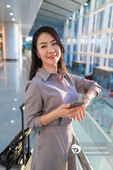 商务女士在机场拿着手机