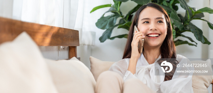 Asian beautiful girl talking on the phone, sitting in the living room.