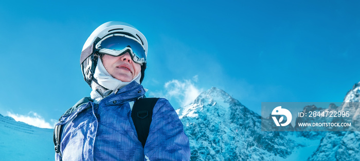 Skier female portrait in safe ski helmet and goggles with picturesque snowy Tatry mountains background.