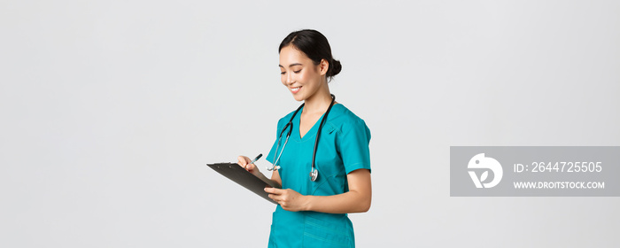 Healthcare workers, preventing virus, quarantine campaign concept. Beautiful smiling asian doctor, nurse running checkup in hospital, looking at clipboard with patient results, examine people