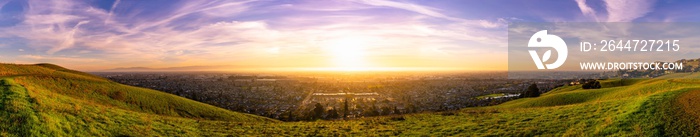 Expansive sunset panorama comprising the cities of east San Francisco bay, Fremont, Hayward and Union City; green hills visible in the foreground; San Francisco Bay Area, California