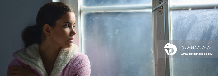 Beautiful ill sad cancer patient girl in pajamas  looking through hospital window