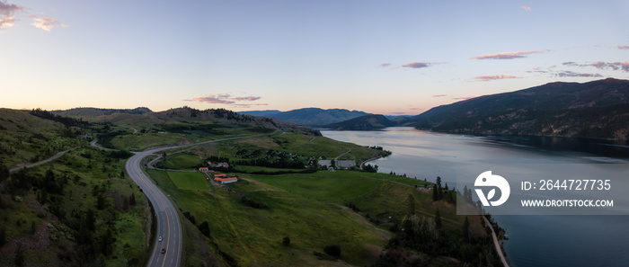 Aerial panoramic view of a highway near Kalamalka Lake during a vibrant summer sunset. Located between Kelowna and Vernon, BC, Canada.