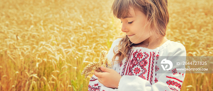 A child in a field of wheat in an embroidered shirt. Ukrainian. Selective focus.