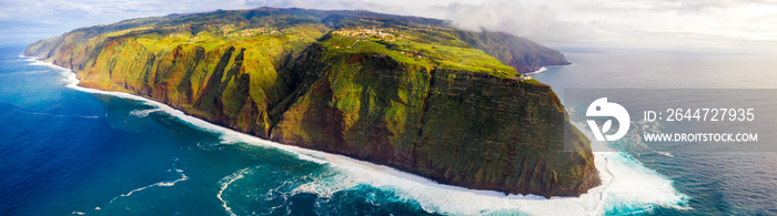 Aerial view of the ocean island cliffs with huge white waves and crystal blue water