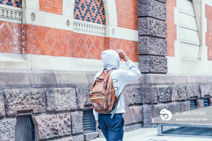 Black guy in a gray hoodie with hood walking on city street