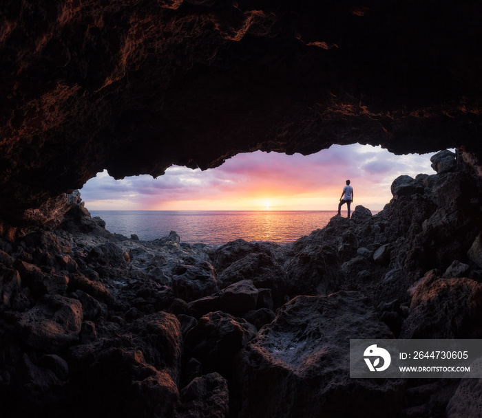 Boy watching a sunset through a cave at Le Souffleur in Saint-Leu, Reunion Island