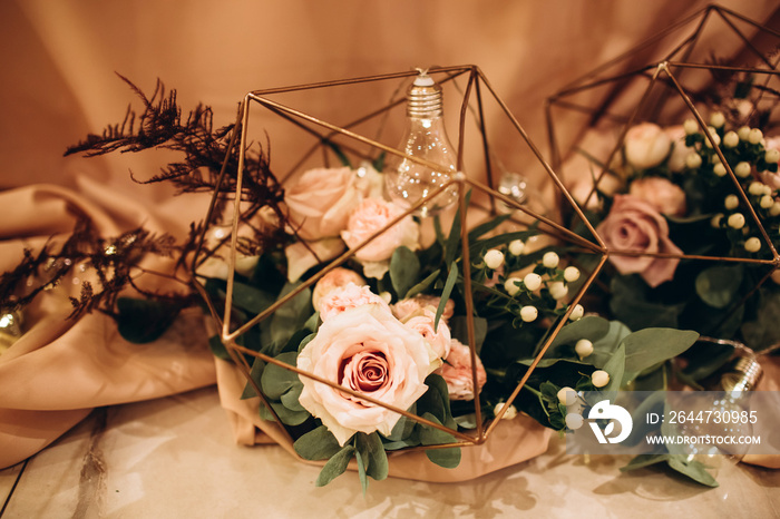 Wedding. Banquet. Beautiful and creative composition of a variety of pale pink flowers and candles that decorated the table for the newlyweds. Modern wedding decoration with geometric elements.