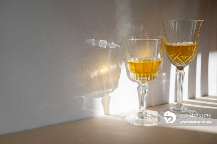 Alcohol drink in crystal glasses, sun light, shadows. Brandy or whiskey drink creative natural light.