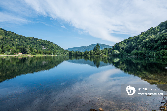 Panoramic view of mountains, trees and clouds perfectly reflected in a blue lake