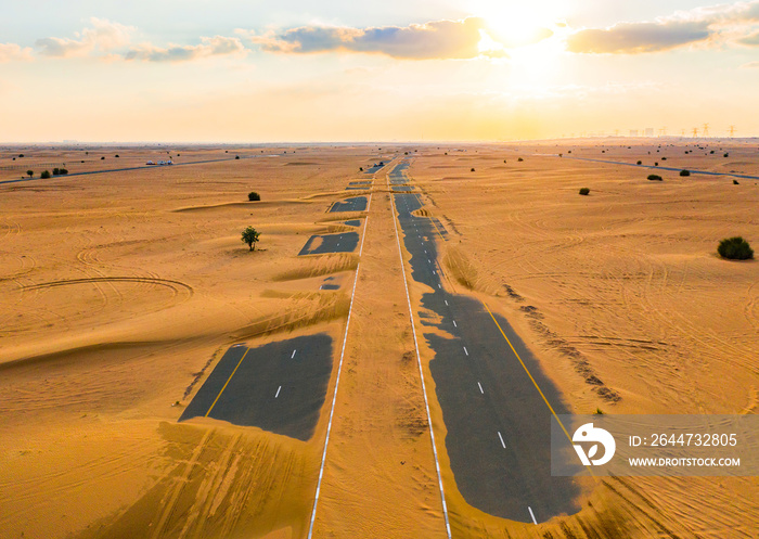 Aerial view of half desert road or street with sand dune in Dubai City, United Arab Emirates or UAE. Natural landscape background at sunset time. Famous tourist attraction. Top view.