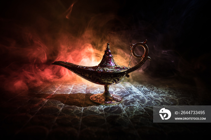 Lamp of wishes concept. Antique Aladdin arabian nights genie style oil lamp with soft light white smoke, Dark background.