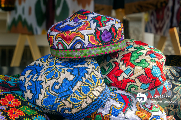 Traditional Asian headdresses with an embroidered colored thread of national ornament in a street market shop