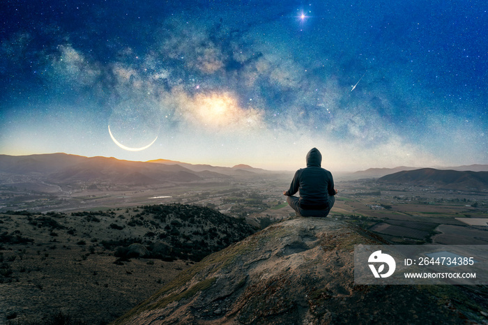 person on the hill outdoors meditating or praying at night with Milky Way and Moon background