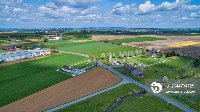 A Beautiful Aerial View of Farm Countryside with Patches of Colored Fields with White Fully Clouds and Shadows