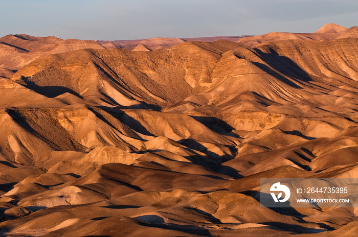 Sunrise view of light and shadow of the expansive, mountain landscape of the Judean Desert in Israel.