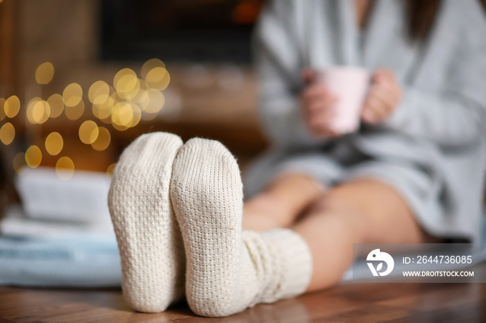 Woman in warm socks relaxing at home on winter day