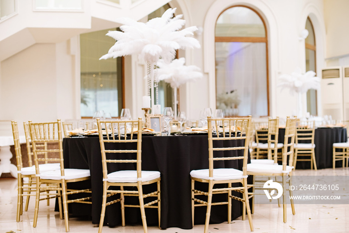 Black tablecloths on big, round tables for a wedding lunch.