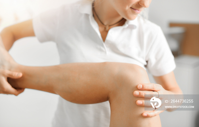 Professional therapist giving relaxing leg massage treatment to athlete woman in therapy centre.